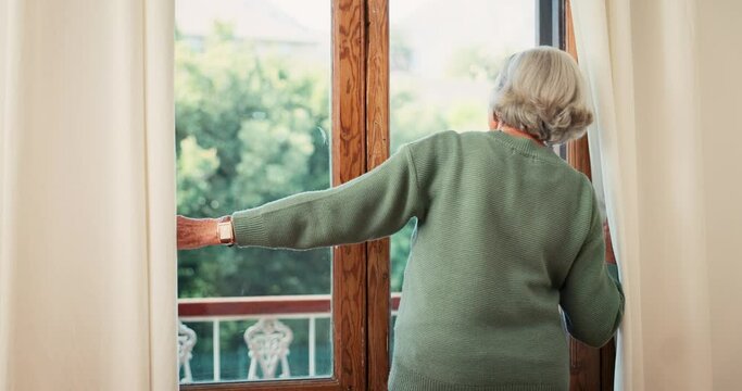Senior, woman and open of curtain in home for fresh, air or morning in bedroom in back view. Back, grandmother and alone for looking by window for outside, nature or trees on vacation in retirement