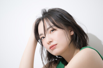 Fototapeta premium 座って髪をかき上げるカジュアルな女性 顔のクローズアップ ヘアケアや美容のイメージの真剣な表情