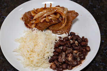 The most traditional Brazilian lunch dish, black beans, rice and onion steak