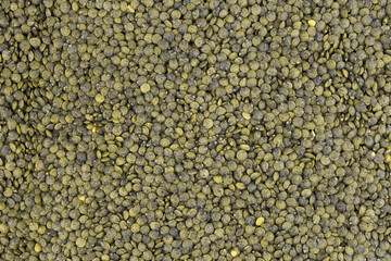 Crop of many dry green lentil grains on flat surface as background