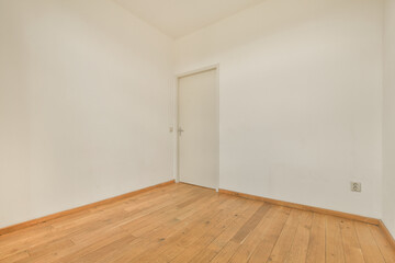 Fototapeta na wymiar an empty room with white walls and wood flooring on the right, there is a door in the corner
