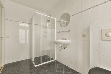 a bathroom with black and white tiles on the floor, shower stall and toilet in the room is very...