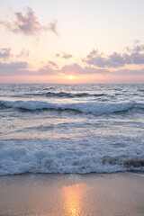 sun sets on a dramatic cloudy sky over the Mediterranean Sea horizon with a warm, golden glow. The sea's waves  magical tranquil seascape