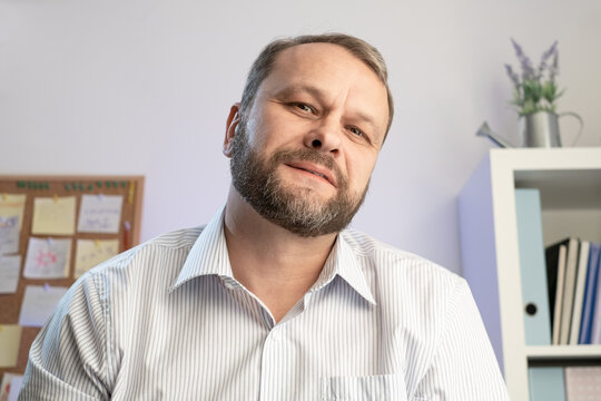 A middle-aged man positive smile, he looks at the camera while engaged in online video calls and live video conference chat using a computer remote communication.