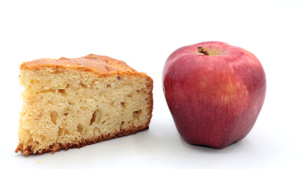closeup of a slice of homemade apple pie with a red apple next to it on a white background