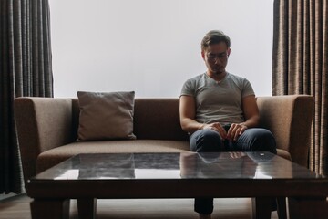 Lonely asian man sits on the sofa thinking of his lover.