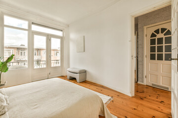 Fototapeta na wymiar a bedroom with wood flooring and white walls, including a large bed in the center of the room is an entry way to