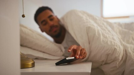 Couple at home in bed with man waking up and turning off alarm on mobile phone before getting up - shot in slow motion 