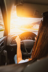 Young woman driving on straight road at sunset