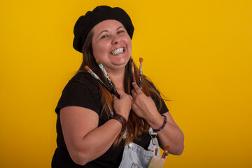 Plus size woman in stylish clothes in studio photos, with facial expressions and with paintbrushes in hand