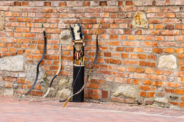 Bows and arrows leaning against a brick wall