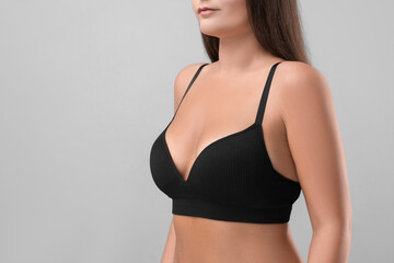 Woman with beautiful breast on light grey background, closeup. Space for text