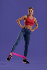 Athletic woman exercising with elastic resistance band on purple background