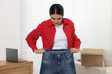 Young woman with just unpacked new jeans at home. Online shopping