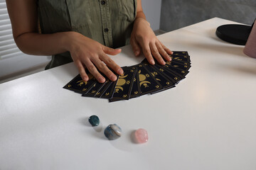 Astrologer predicting future with tarot cards at table indoors, closeup