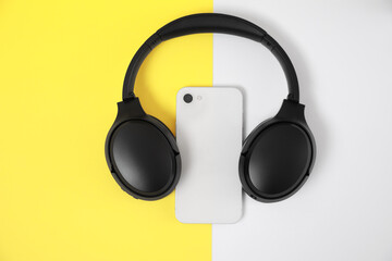Modern wireless headphones and smartphone on color background, top view