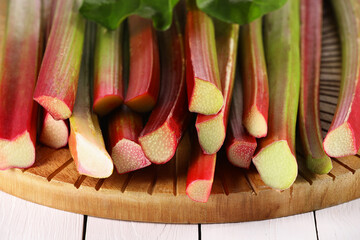 Many cut rhubarb stalks on white wooden table, closeup