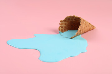 Melted ice cream and wafer cone on pink background, closeup