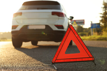 Warning triangle and broken car on roadside, selective focus