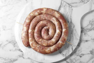 Raw homemade sausage on white marble table, top view