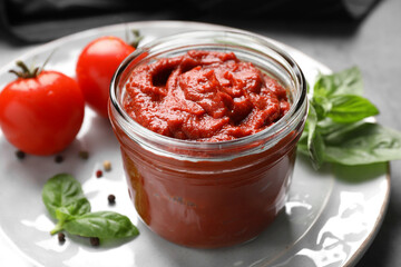 Jar of tasty tomato paste and ingredients on table, closeup