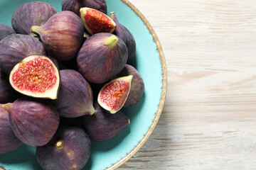 Plate with fresh ripe figs on white wooden table, top view. Space for text