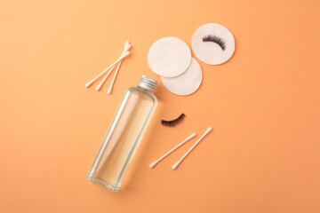 Flat lay composition with makeup remover and false eyelashes on pale orange background