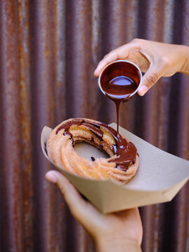 Pouring hot chocolate over donut churro