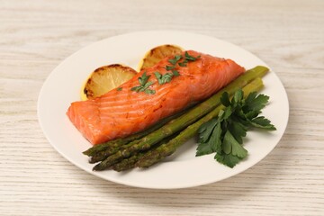 Tasty grilled salmon with asparagus and lemon on white wooden table, closeup