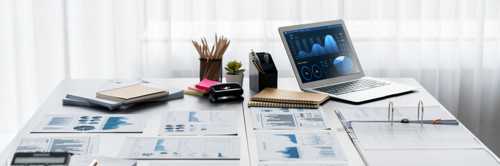 Data analysis dashboard display on laptop screen on office table with financial papers by Fintech BI technology for business marketing and strategy in corporate meeting room. Insight