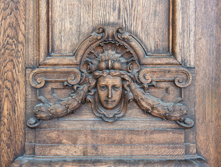 Wooden carving of a woman's head with intricate details, part of the side entrance of Royal Swedish...