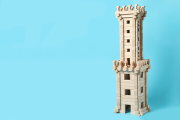 Wooden tower on light blue background, space for text. Children's toy