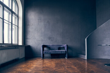 Against the background of large windows, an elegant black sofa. It reflects the living space in...