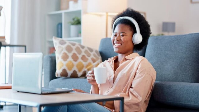 Woman laughing while watching funny series on a laptop at home. Happy female drinking coffee while enjoying a weekend of hilarious entertainment. Streaming comedy movies and sitcom shows online