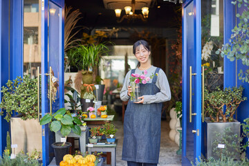 花屋で働くエプロンをきた日本人の女性 - obrazy, fototapety, plakaty
