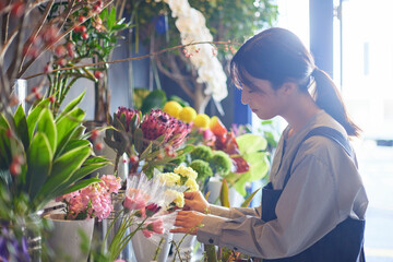花屋で働くエプロンをきた日本人の女性 - obrazy, fototapety, plakaty