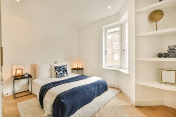 a bedroom with white walls and wood flooring, along with a large bed in the room has a blue blanket on it