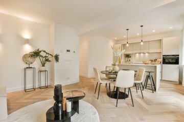 a kitchen and dining area in a living room with white walls, wood flooring and an open - plan kitchen