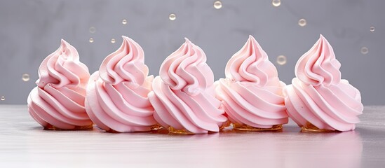 Pink meringue adorns a silver surface taking the shape of delicate swirls and rounded structures