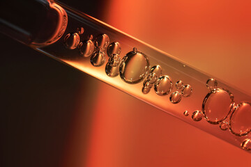 A dropper with sunscreen body serum in the orange sunset light.