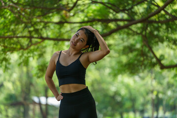 Young Asian woman wearing black exercise clothes Warming up Stretch your knees and legs. After exercising in the park