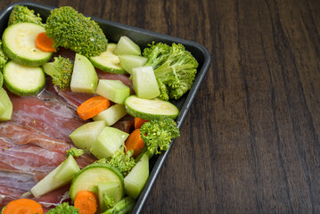 Tray with raw fish fillets and vegetables on wooden table. Healthy food.