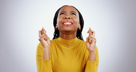 Fingers crossed, praying and black woman in studio with sign of good luck for bonus, prize or...