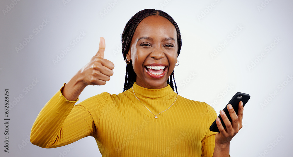 Wall mural Phone, thumbs up and portrait of happy black woman in studio with review, feedback or vote on grey background. Success, emoji and face of lady model with thank you sign for smartphone, app or support