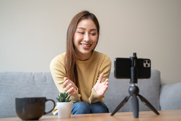 Young asian woman recording herself interview video via smartphone for her vlog.