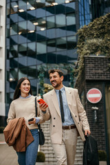 Two business partners discussing plans on a busy city street while one holding their phone