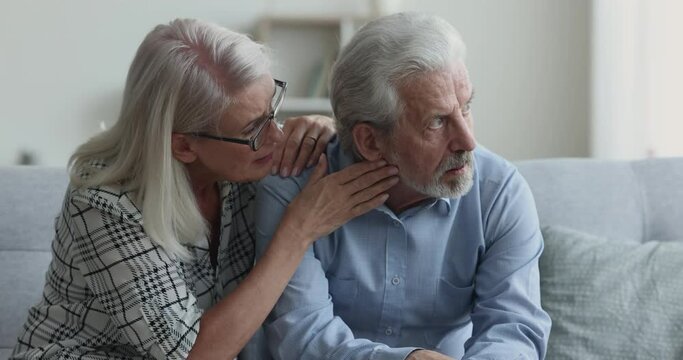 Caring sympathetic senior wife giving comfort, support to stressed frustrated older husband, consoling man, speaking with empathy, patting shoulder, holding hand. Retired couple getting problems