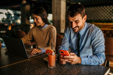 Couple multitasking with laptops, phones, and drinks in a cozy cafe