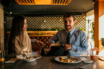 A diverse business pair, a man and a woman, at a restaurant, deciding what to order for lunch