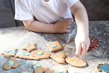 Little boy is decorating ginger cookies on the kitchen